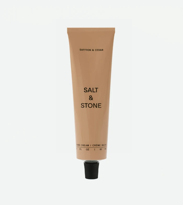 Beige squeeze tube of skincare labeled 'Saffron & Cedar' with 'Salt & Stone' brand, standing upright.