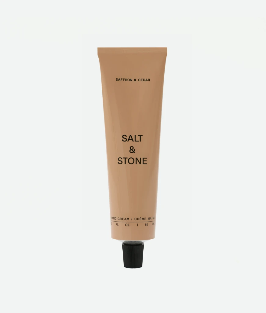 Beige squeeze tube of skincare labeled 'Saffron & Cedar' with 'Salt & Stone' brand, standing upright.