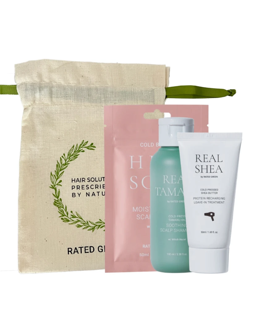 Beige fabric tote with green strap containing a hair care gift set: pink pouch, teal bottle, and white Real Shea tube.