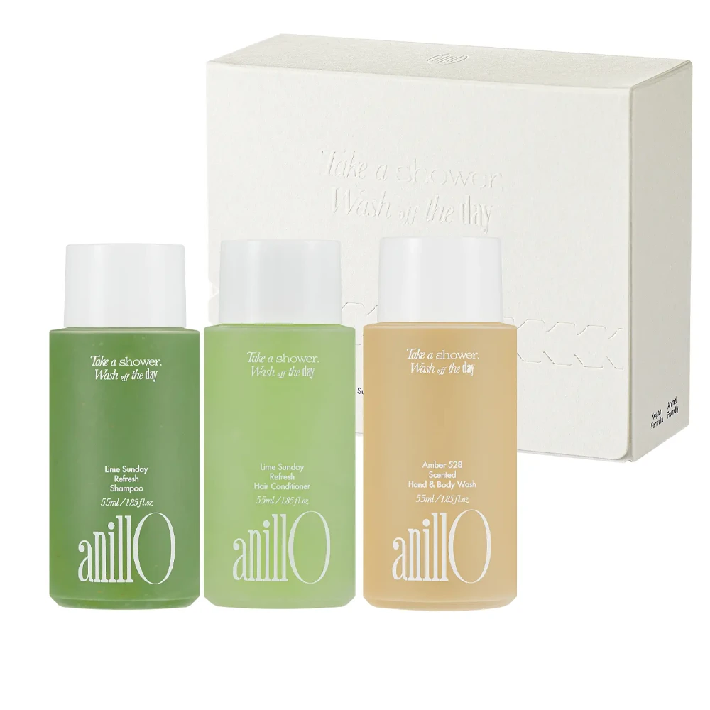 Three travel-size Anillo personal care bottles (shampoo, conditioner, hand & body wash) in green and amber hues with a white box behind them.