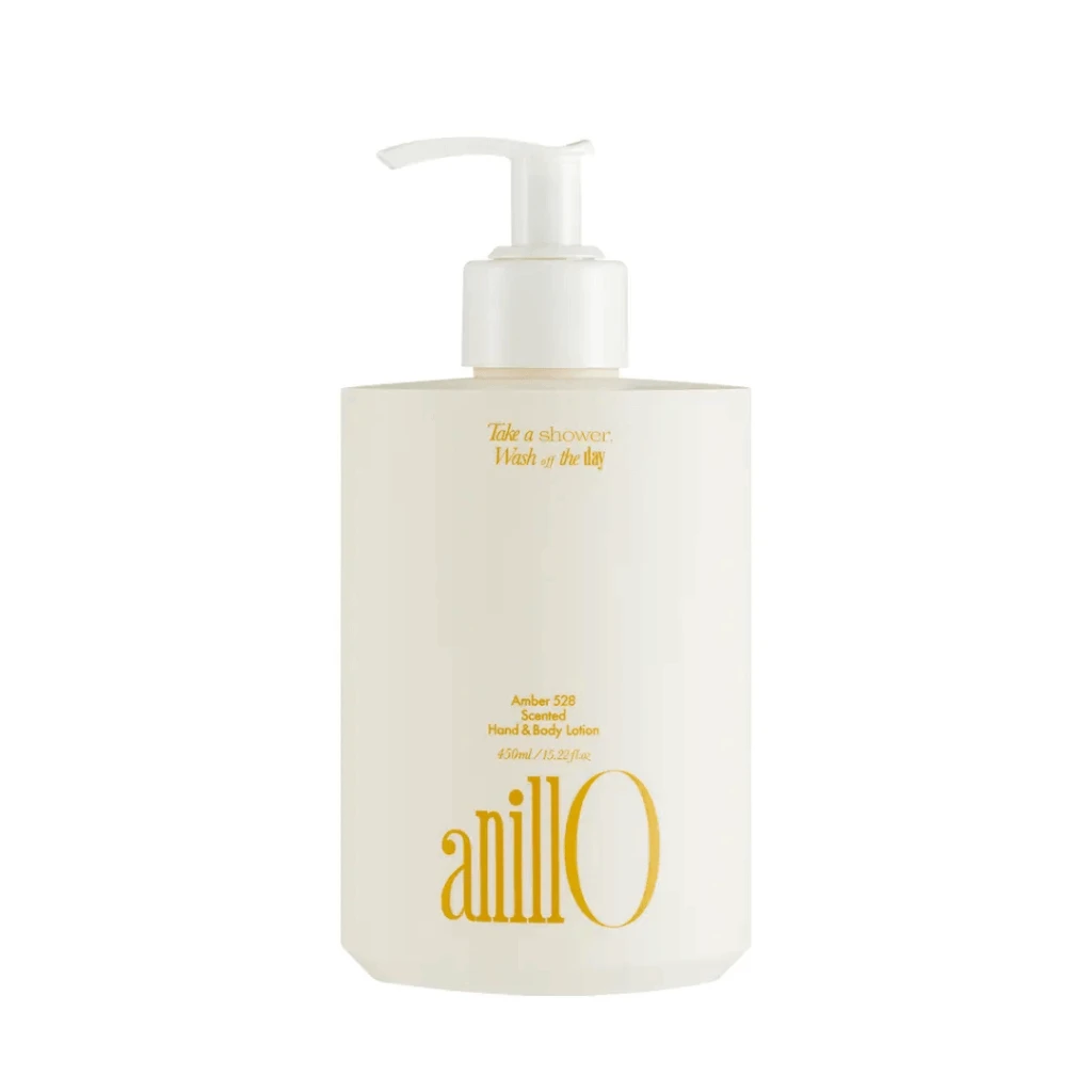 White pump lotion bottle with gold text, labeled 'anill0' (Amber 528 scented hand & body lotion), single-product shot on white background.