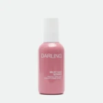 Close-up of a pink bottle with a white cap, labeled 'DARLING' with 'MILKY HAIR SCREEN' text on the label against a white background.
