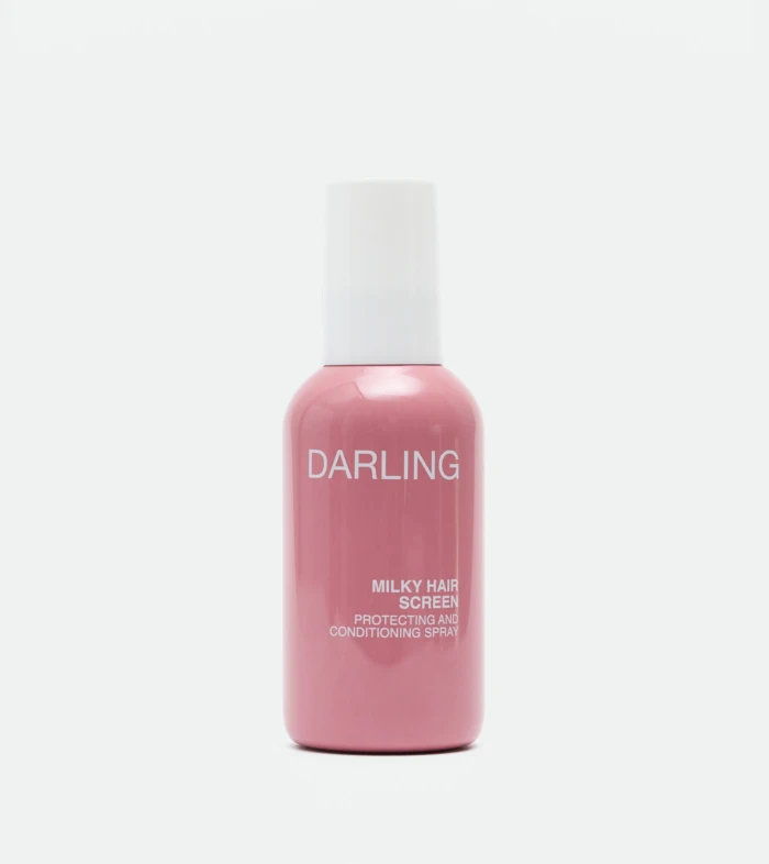 Close-up of a pink bottle with a white cap, labeled 'DARLING' with 'MILKY HAIR SCREEN' text on the label against a white background.