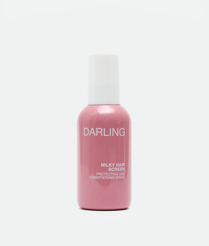 Close-up of a pink bottle with a white cap, labeled 'DARLING' with 'MILKY HAIR SCREEN' text on the label against a white background.