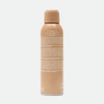Tall peach-colored spray bottle with a rounded cap, centered against a pale gray background; minimal product labeling is visible on the bottle edgey surface.