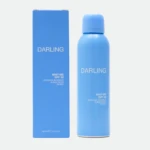 Bright blue sunscreen packaging: a tall box on the left and a matching spray bottle on the right, both labeled DARLING with small print noting Mist-Me SPF 50 cooling invisible sunscreen spray.