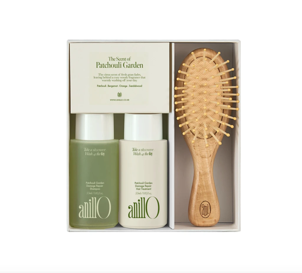 Gift set containing two AnilO hair products (shampoo and hair treatment) and a wooden bristle brush in a white box, ready as a gift