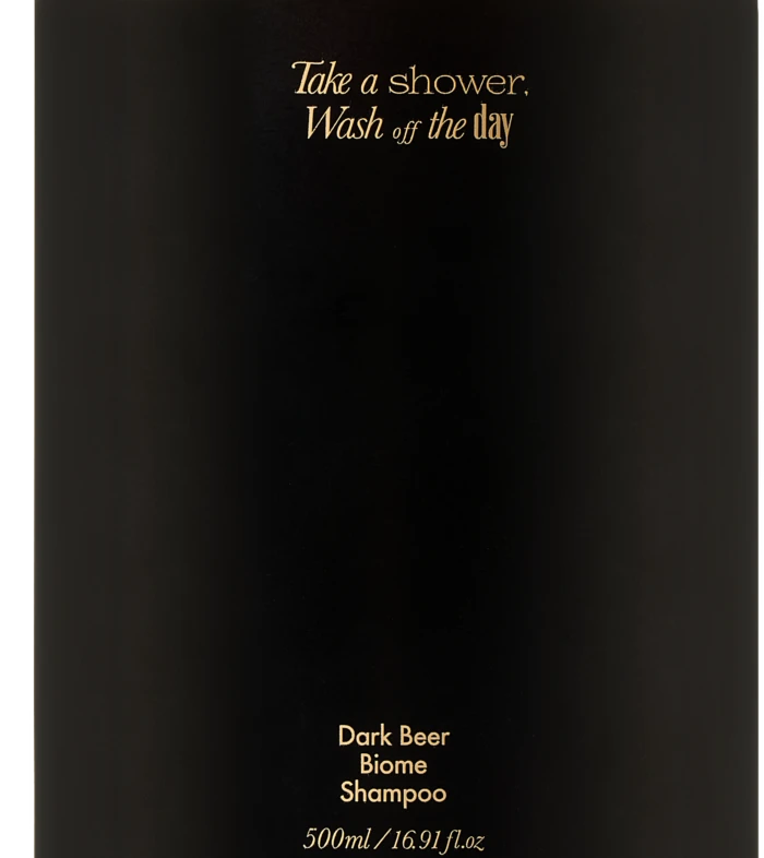 Black pump shampoo bottle with gold text: 'Take a shower, Wash off the day' and 'Dark Beer Biome Shampoo'
