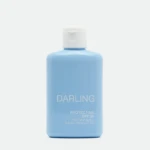 Close-up of a light blue sunscreen bottle with a white flip-top cap, showing the label 'DARLING' and 'PROTECT-ME SPF 50'.