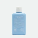 Close-up of a blue sunscreen lotion bottle with a white cap, standing upright against a pale background.