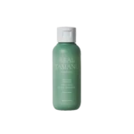 Green bottle of Real Tamanu soothing scalp shampoo with a white cap, set against a black background.