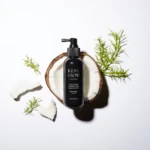 Real Grow scalp spray bottle in a coconut shell with rosemary sprigs on a white background (brand name visible).