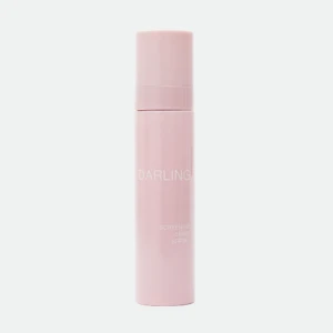 Vertical close-up of a pink cosmetic bottle with text, labeled 'DARLING' and 'SCREEN-ME SPRAY SPF 50+' (tinted skin-tone bottle)