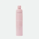 Close-up of a pastel pink sunscreen spray bottle with a pump nozzle against a pale background, label reads DARLING.