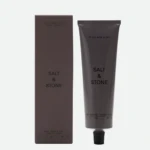 Box and tube of Salt & Stone Black Rose & Oud body lotion with brown packaging, shown side by side.