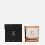 Black Salt & Stone box beside a peach-colored candle in a glass jar with a white label reading 'Salt & Stone'.