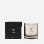 Minimalist black box labeled 'SALT & STONE' next to a clear-glass candle jar with a white 'SALT & STONE' label.