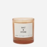 Amber glass candle labeled 'Salt & Stone' with a simple white label, set against a light background.