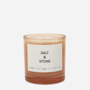 Amber glass candle labeled 'Salt & Stone' with a simple white label, set against a light background.
