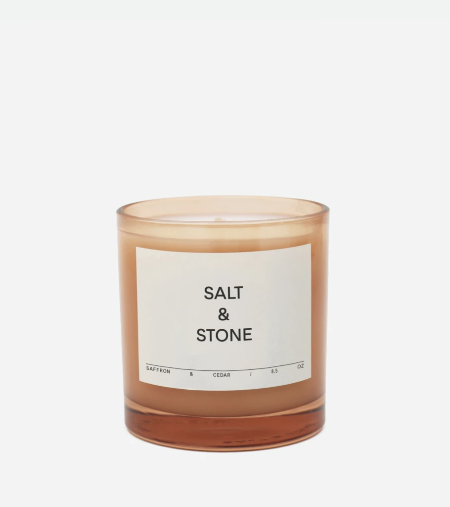Amber glass candle labeled 'Salt & Stone' with a simple white label, set against a light background.
