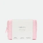 White box with pastel text reading 'DARLING' resting on a pink knitted blanket against a light background.