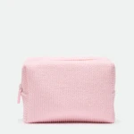 Pink knitted tote bag with a zipper, shown against a white background while resting on a surface.