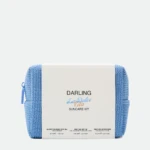 White product box labeled DARLING sits on a blue knitted backdrop, a sun care kit display.