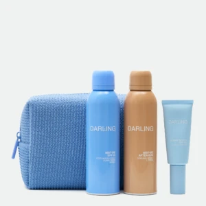 Three sunscreen bottles in blue and tan colors stand upright in front of a textured blue towel on a light background.