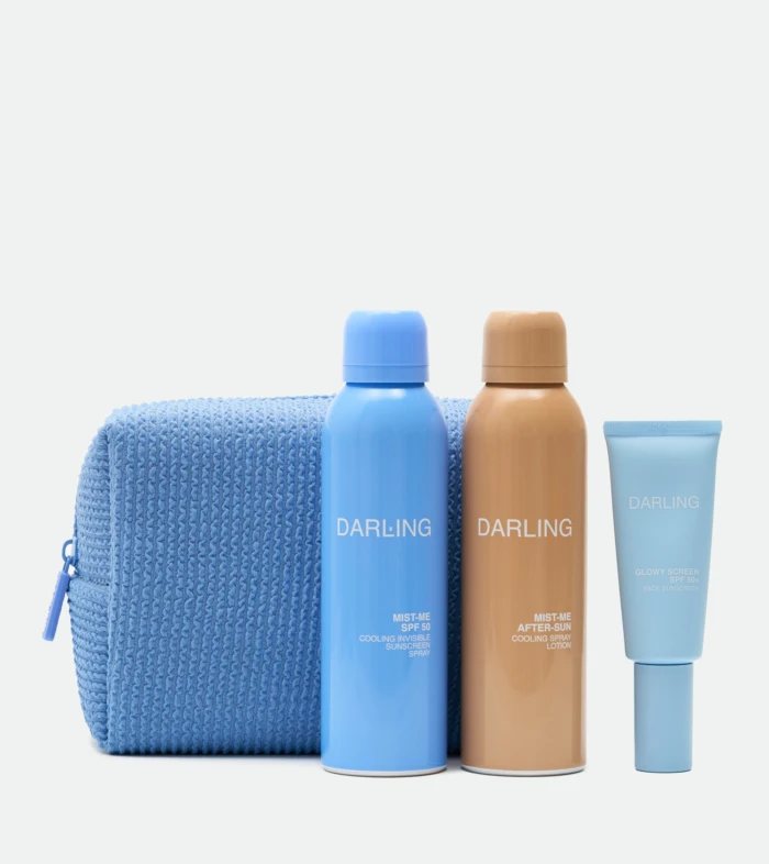 Three sunscreen bottles in blue and tan colors stand upright in front of a textured blue towel on a light background.