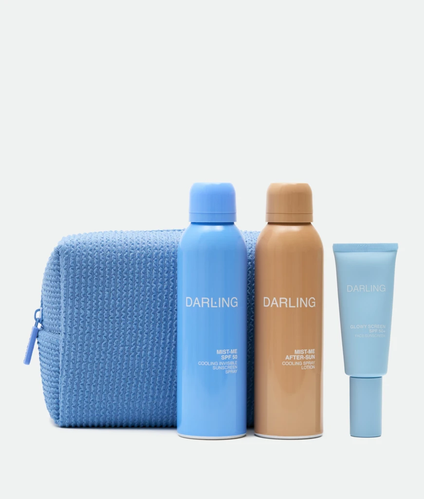 Three sunscreen bottles in blue and tan colors stand upright in front of a textured blue towel on a light background.