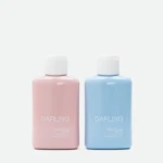 Two Darling sunscreen bottles in pink (left) and blue (right) standing side by side.