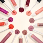Circle arrangement of YOUNG?G lip gloss tubes in diverse pinks, reds, and nude shades with applicators.