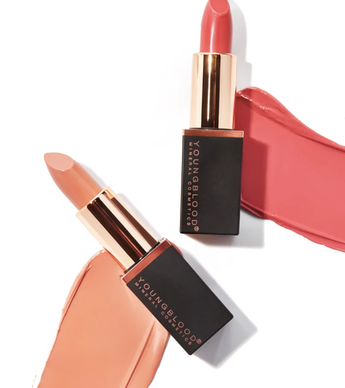 Two lipstick bullets with pink and nude shades against a white background, with swatches of lipstick smeared nearby for a makeup product aesthetic.