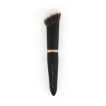 Close-up of a makeup brush with a black handle and rose-gold ferrule, bristles fanned out; 'YOUNGBLOOD' branding visible on the handle.