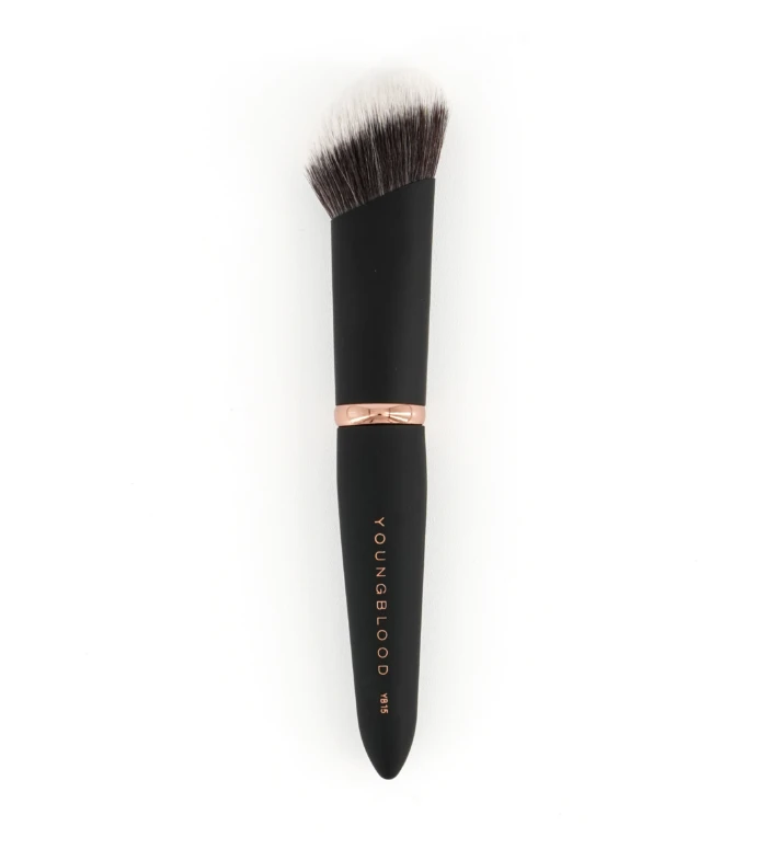 Close-up of a makeup brush with a black handle and rose-gold ferrule, bristles fanned out; 'YOUNGBLOOD' branding visible on the handle.