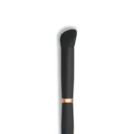 Close-up of a black makeup brush with soft bristles and a copper ferrule on a white background