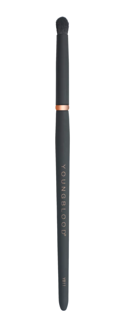 Slim black makeup brush with dense bristles, rose-gold collar, and 'YOUNGBLOOD' printed along the handle.