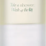 Tall white bottle with a frosted cap, labeled Neroli Wood Glow Hair Mist (70 mL) and the slogan 'Take a shower, Wash off the day'.