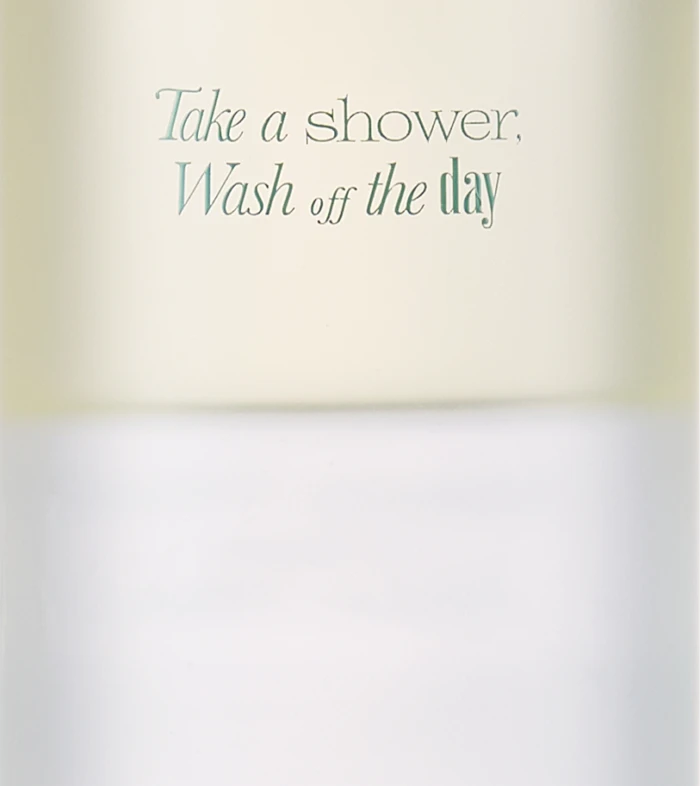 Tall white bottle with a frosted cap, labeled Neroli Wood Glow Hair Mist (70 mL) and the slogan 'Take a shower, Wash off the day'.