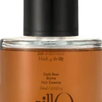 Close-up of a glass bottle with an orange liquid and a black pump, labeled Dark Beer Biome Hair Essence (50 ml).