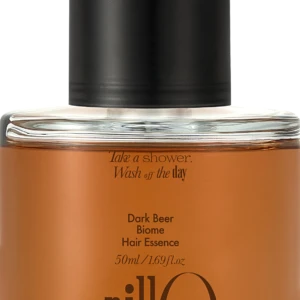 Close-up of a glass bottle with an orange liquid and a black pump, labeled Dark Beer Biome Hair Essence (50 ml).