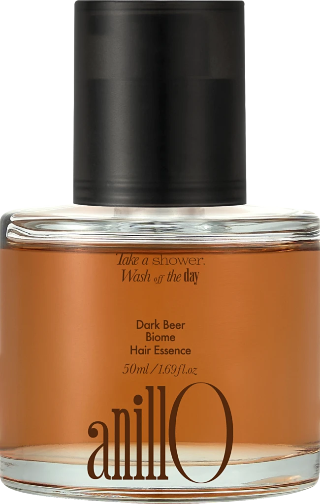 Close-up of a glass bottle with an orange liquid and a black pump, labeled Dark Beer Biome Hair Essence (50 ml).