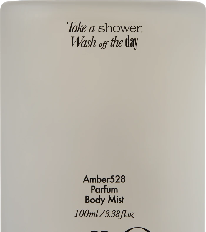 Cream perfume bottle with black cap; label reads “Take a shower, Wash off the day,” and “Amber528 Parfum Body Mist, 100ml”