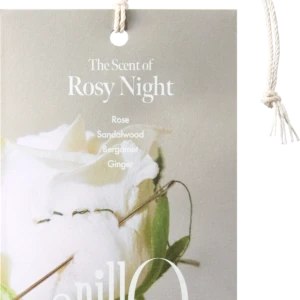 Beige gift tag with a white rope handle reading 'The Scent of Rosy Night' and listing notes: Rose, Sandalwood, Bergamot, Ginger, with a floral image in the background