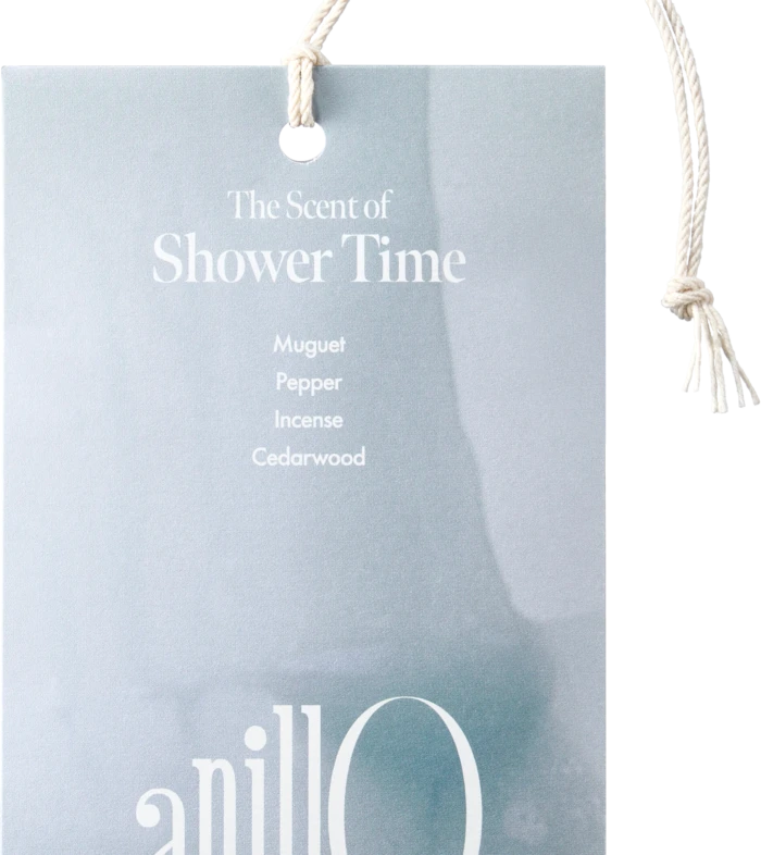 Light blue tag with white rope reading 'The Scent of Shower Time' and notes: Muguet, Pepper, Incense, Cedarwood.