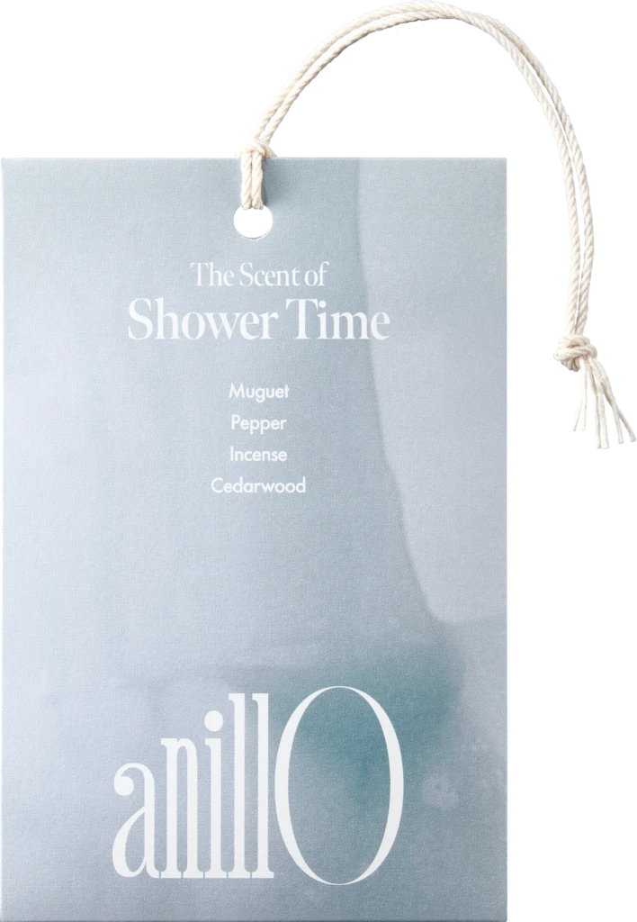 Light blue tag with white rope reading 'The Scent of Shower Time' and notes: Muguet, Pepper, Incense, Cedarwood.