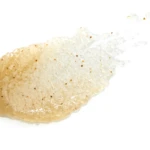 Close-up of a golden-brown, breaded fried piece with a bubbly crust on a white background, showing oil sheen and small brown specks.