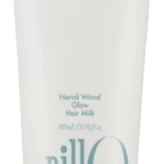 White hair milk tube labeled Neroli Wood Glow Hair Milk with blue slogan 'Take a shower, Wash off the day' and a large blue 'anillo' logo on the side.