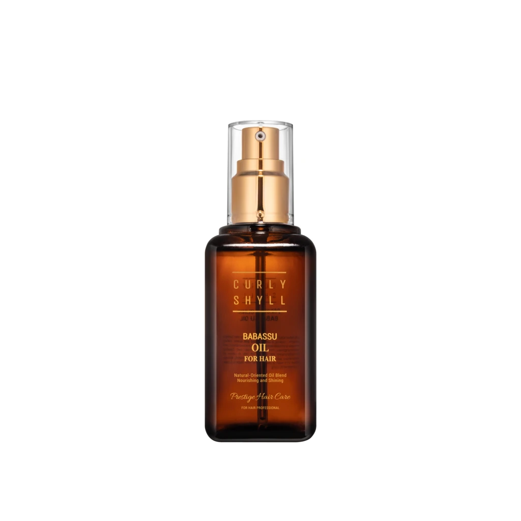Brown glass hair product bottle with a gold spray pump and clear cap, labeled Babassu Oil for Hair in gold lettering.