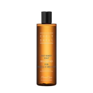 Orange shampoo bottle with a black cap, label reads 'Root Remedy Scalp Shampoo' for normal and dry scalp against a white background in a close-up shot.